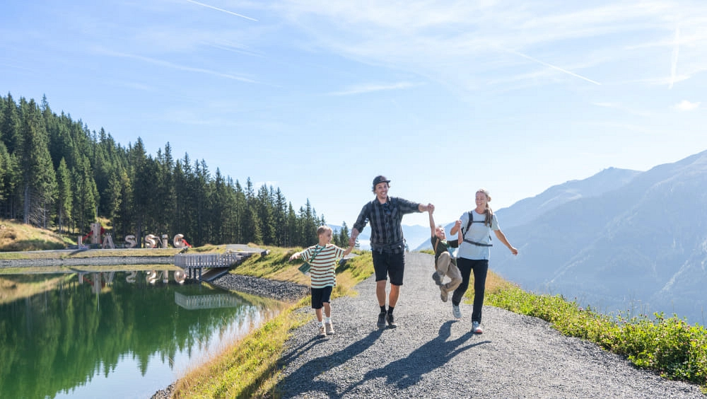 Familie beim Wandern am Reiterkogel mit Bergsee im Hintergrund